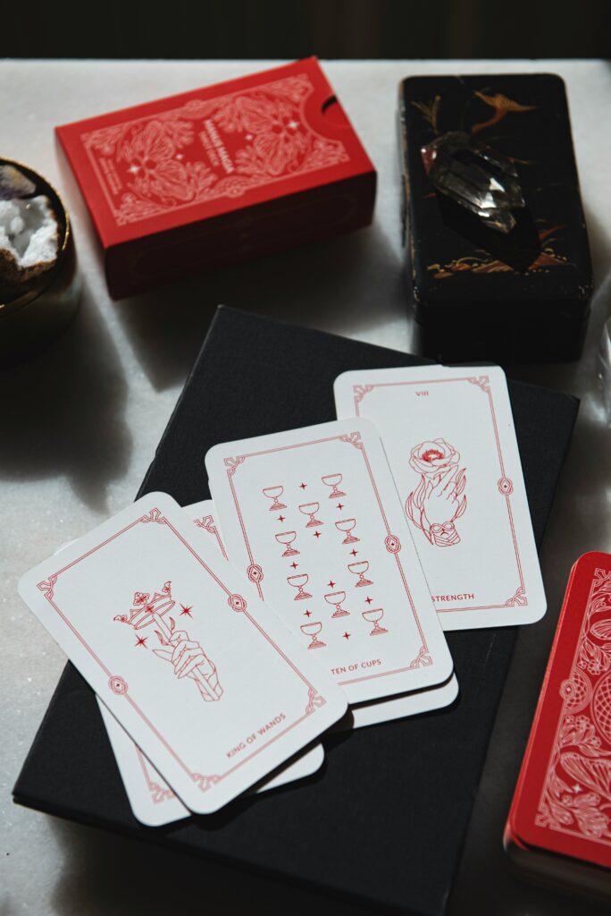 A three card spread of tarot white cards with red designs. 